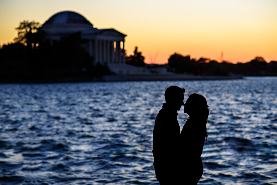 An engaged couple kiss with the dc sunset behind them.